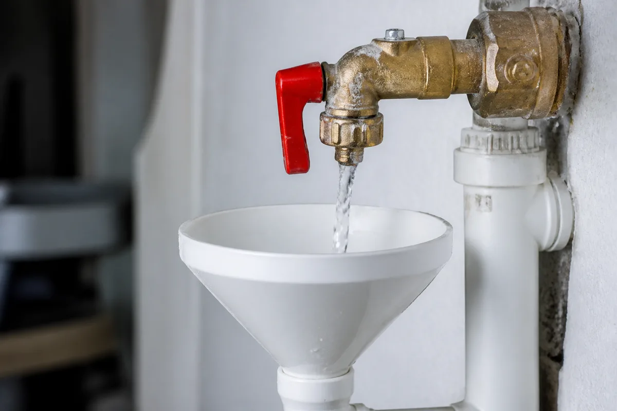 Groupe de sécurité rouge d un chauffe-eau purgé au-dessus d un siphon, filet d eau en cours d écoulement